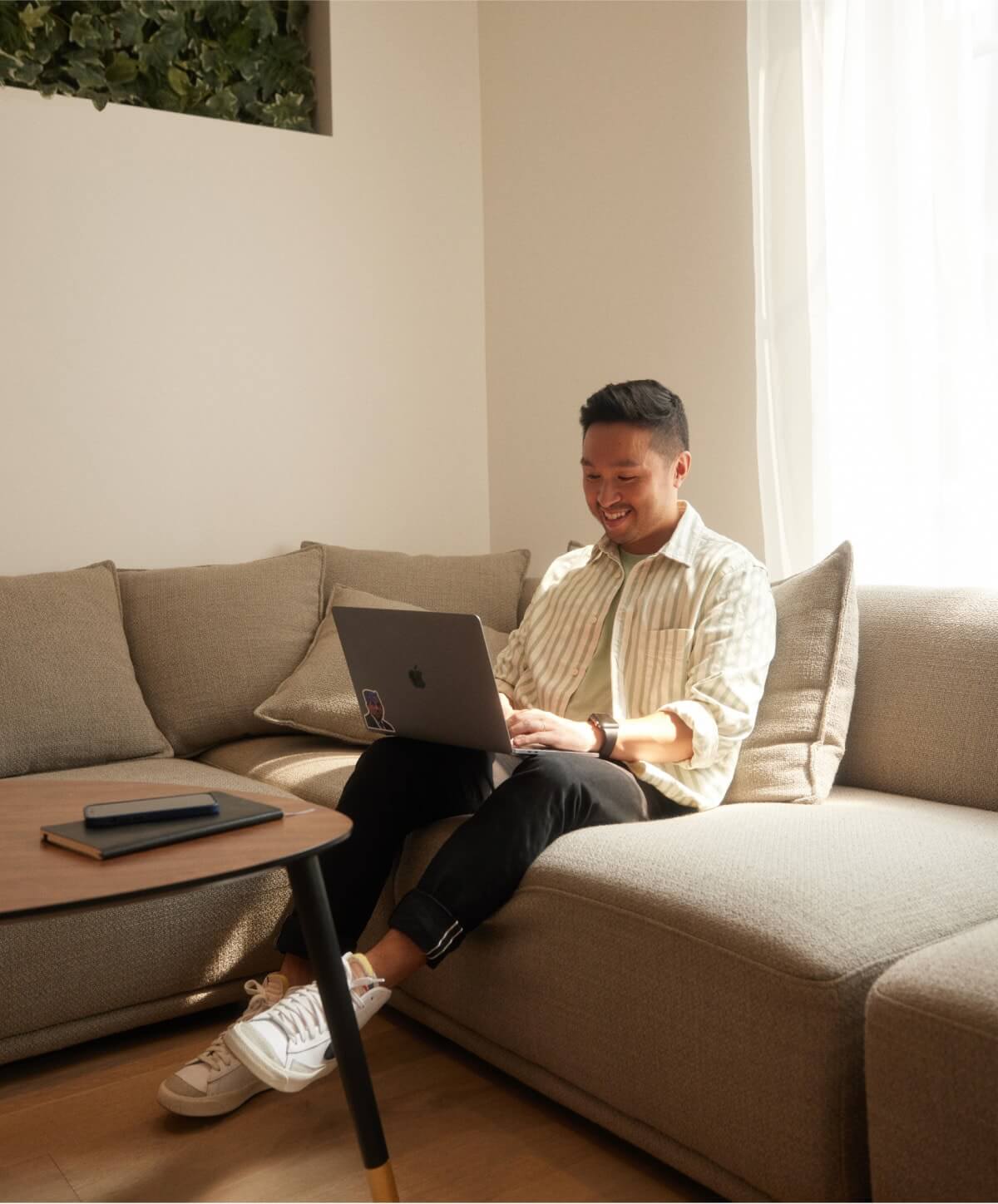 Content while working from home: A smiling individual working from their couch, showcasing productivity and comfort in a remote work environment